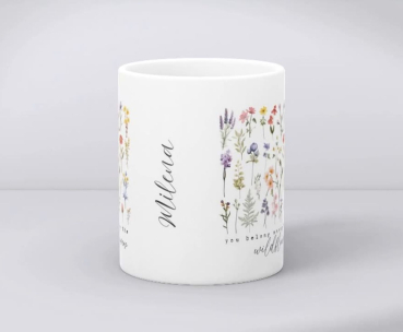 Preview: Personalisierte Tasse mit Blumen und Name – You belong among the wildflowers | Geschenk für Naturfreundinnen Preview: Detailansicht einer weißen Keramiktasse mit Wildblumenmotiv, dem Zitat „You belong among the wildflowers“ und dem personalisierten Namen „Milena“ in eleganter Schrift.
